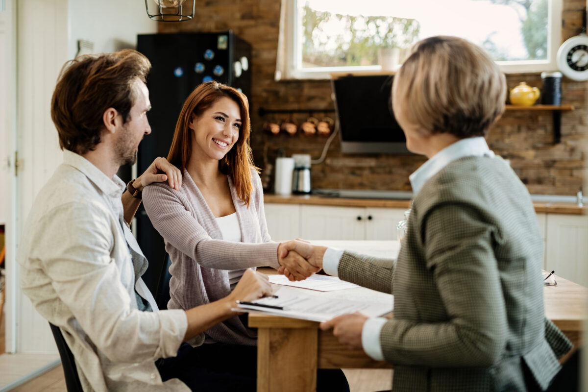 Clientes satisfechos firmando contrato de compra con asesora inmobiliaria en Torroella de Montgrí